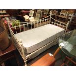 A modern white metal day bed with trundle base