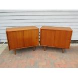 A pair of Danish teak cabinets each with twin sliding doors, raised on tapering legs. 87.