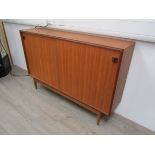 A Danish teak bookcase with twin sliding doors, shelf to interior, raised on short tapering legs.