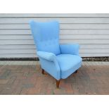 A 1940's Danish high back armchair with blue wool upholstery, raised on stained beech tapering legs.