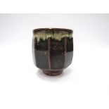 PHIL ROGERS (b. 1951) A stoneware Yunomi with cut sides, tenmoku glaze. Impressed seal.