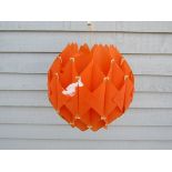 A ceiling light pendant with orange plastic interlocking shade