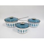 Three Catherine Holm saucepans in white enamel with blue leaf print, blue lids and chrome fittings.