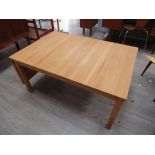 A Danish light oak finish coffee table with drop flap to one end, raised on square legs.