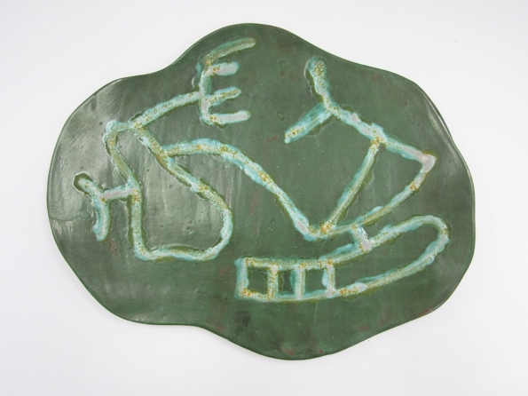 A 1950's French studio pottery green glazed plaque with abstract design. Signed verso.