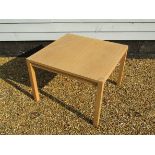 A light oak coffee table, square top, raised on square legs,