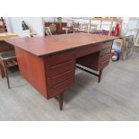 A Danish teak twin pedestal desk with nine drawers, open back, raised on tapering legs 135cm x 74.