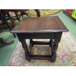 An 18th Century oak stool on turned legs joined by stretchers,