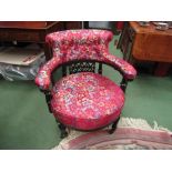 A Victorian ebonised tub chair with floral upholstery on castors