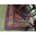 An Eastern wool rug. Blue ground with multiple borders and central stylised motifs.