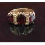 A 9ct gold three stone garnet ring, the central garnet flanked by three clear stones.