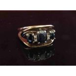 A gold ring set with three oval sapphires,