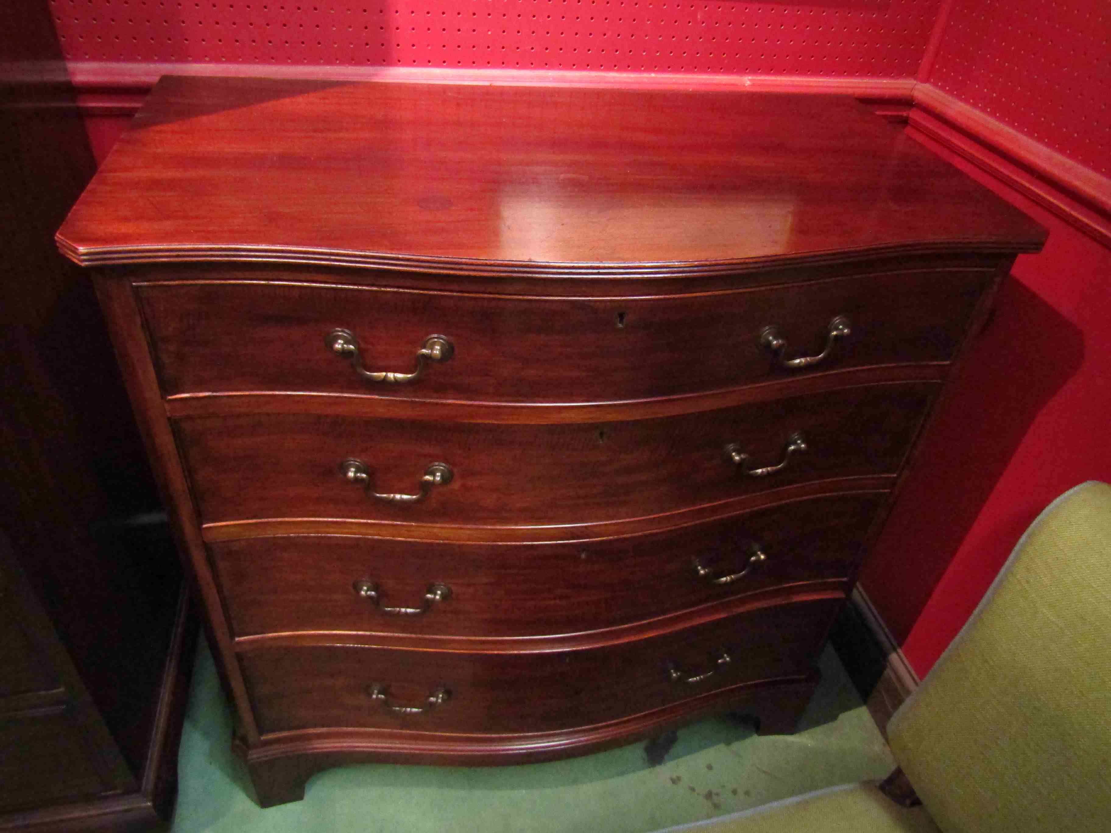 A George III revival mahogany serpentine front chest of four long drawers on bracket feet,