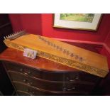A stringed instrument akin to a Japanese Koto, 20 strings with raised bridge,