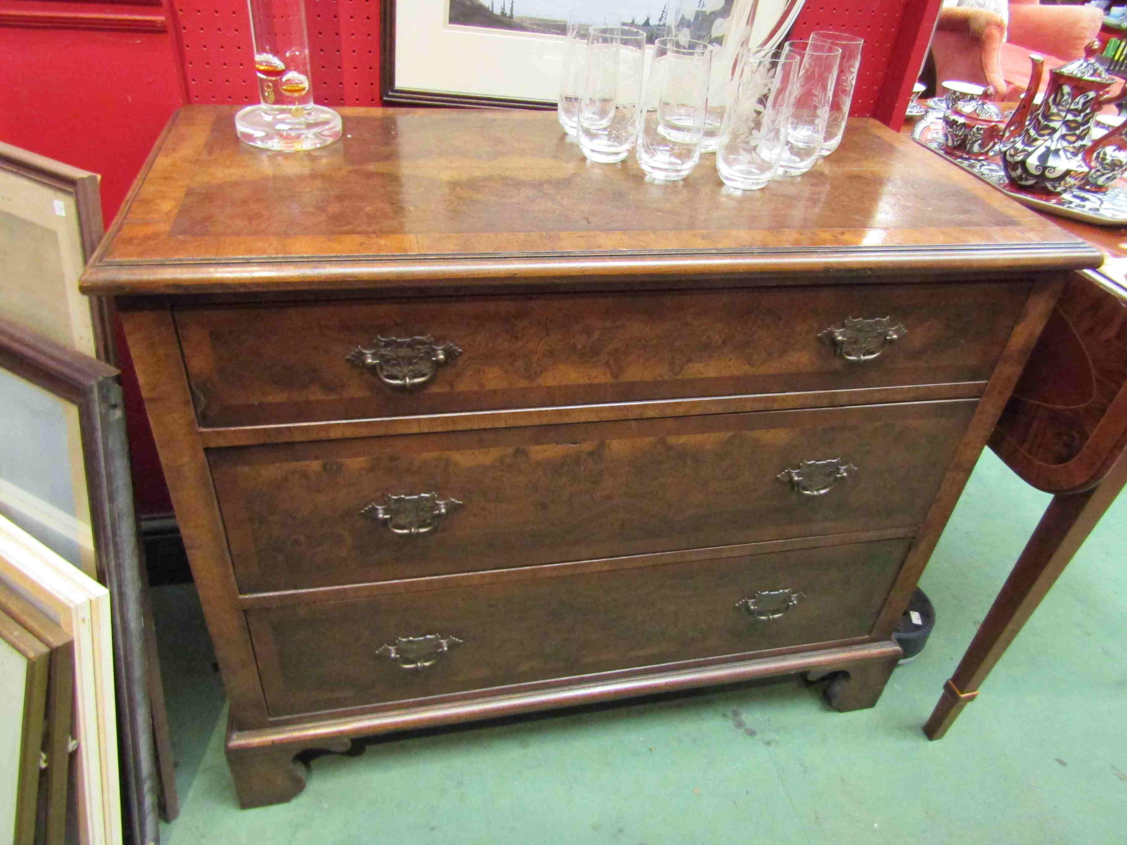 A walnut three drawer chest on bracket feet,