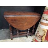 An 18th Century style oak oval top gateleg occasional table the rising leaves over turned legs,