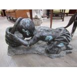 A bronze water feature of a boy drinking from a bucket,