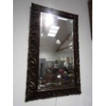 A heavily scroll carved oak framed wall mirror with bevelled glass, 109.