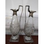 A pair of silver mounted glass oil and vinegar ewers, bird beak sports, right angled handles,