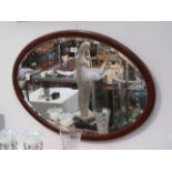 An Edwardian oval mirror with bevelled glass