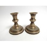 A pair of silver squat form candlesticks, dented, 12cm tall,