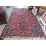 An Eastern wool rug, brown ground, three blue central guls, geometric border, fringing,