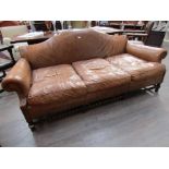 A three seater club leather sofa, worn, with barley twist stretcher,