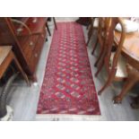 A 20th Century handwoven runner rug with central field decorated with two rows of ascending guls,