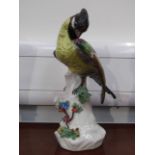 A Continental porcelain figure of exotic bird on branch, applied floral sprays,