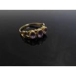 A 9ct gold ring with three oval amethysts, ornately patterned shoulders. Size S/T, 2.
