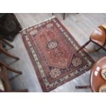 A 20th Century handwoven Persian floor rug with central hexagonal lozenge, floral border,