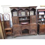 A Georgian style oak heavily carved dresser with shelved and cupboard back over three drawer,