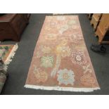 An Oriental pink ground thick pile rug with tasselled fringe,