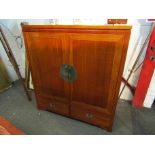 An Oriental style hardwood TV cabinet with cupboard door over two drawers,