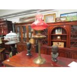 A pedestal brass and cranberry glass oil lamp,