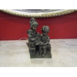 A bronzed figure of boy and girl with teddy,