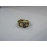 A 9ct gold ring set with three oval opals with scroll engraved shoulders. Size R, 4.