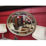 A large oval silvered wall mirror with beveled edges,