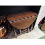An 18th Century style oak oval top gateleg occasional table the rising leaves over turned legs,