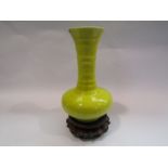 A 19th Century yellow ground Oriental vase with turned neck and flared rim on carved wooden stand,