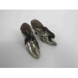A pair of white metal pin cushions in the form of shoes