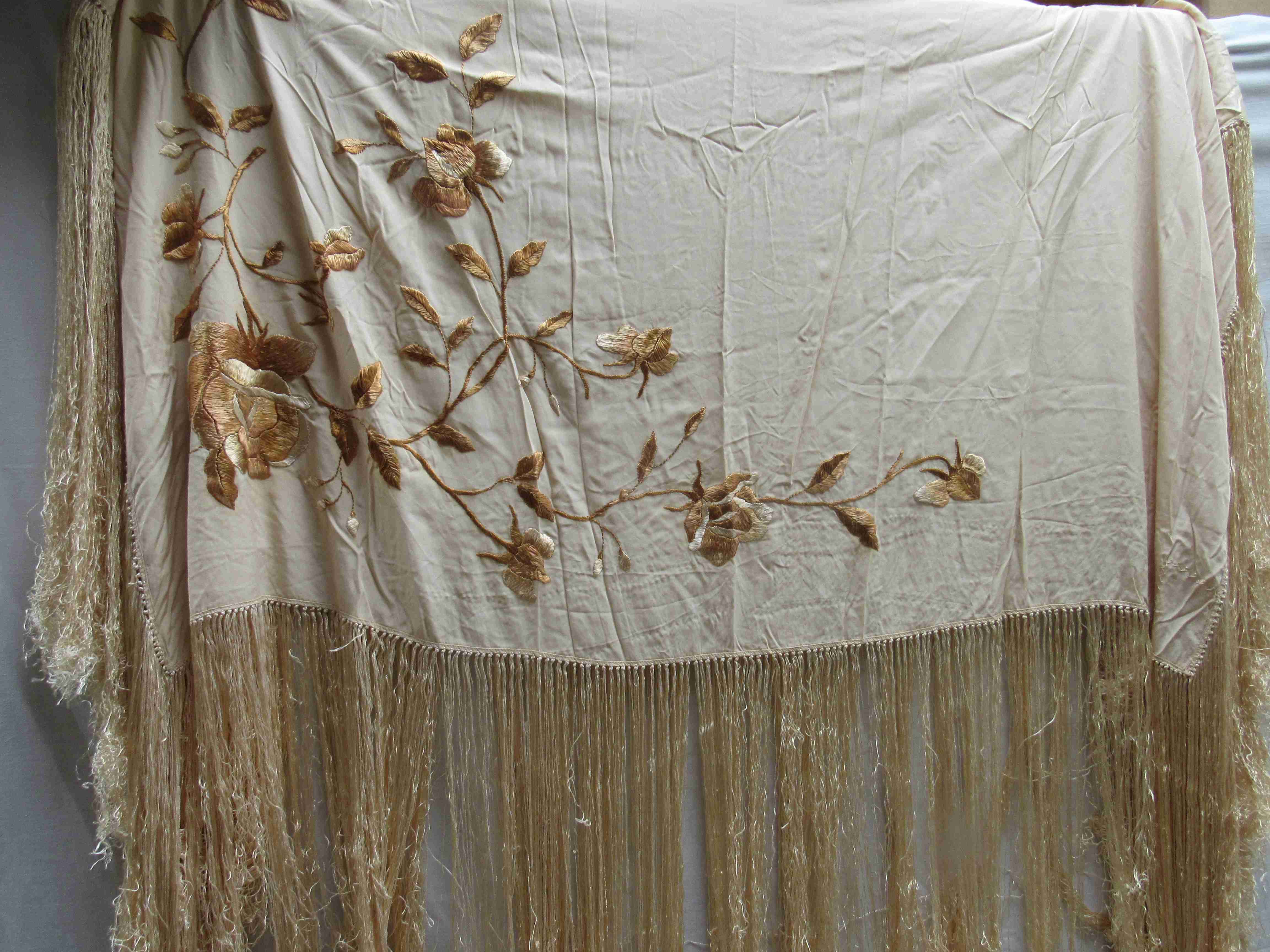 A cream silk shawl with fringing with embroidered golden flowers