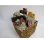 A basket containing an assortment of hats and scarfs including wool examples