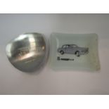 A Triumph Herald glass ashtray and a stainless steel ashtray etched with a picture of a 1911