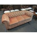 An Edwardian button back Chesterfield three seater sofa on bun feet and castors,