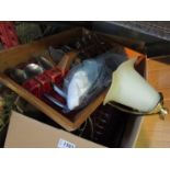 A box containing assorted items including a cranberry glass vase, a pair of vintage tins,