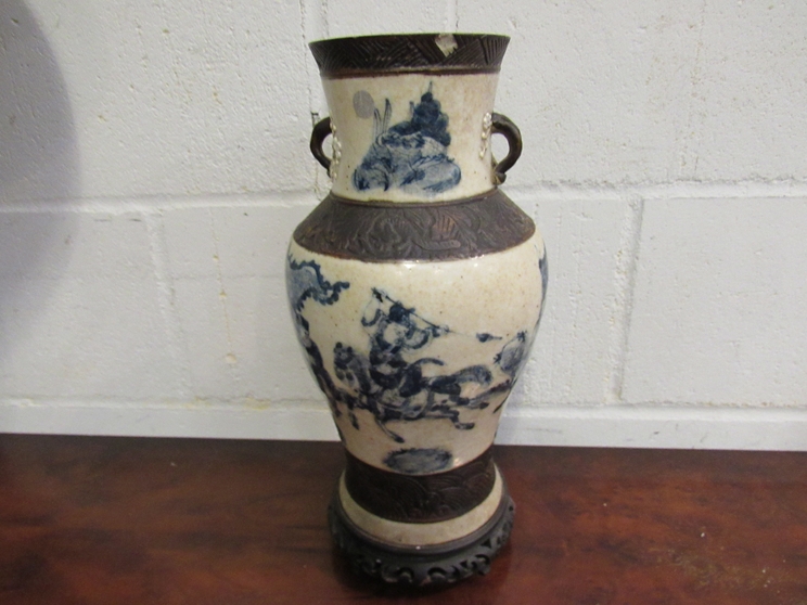 A Chinese vase with warriors on horseback, character marks to base, on carved hardwood stand,