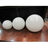 A set of three graduating opaque glass orb form ceiling lights with fittings