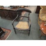 An ebonised elbow chair on turned front legs and stretcher base,