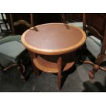 A circular leather topped two tier occasional table, 61cm tall,